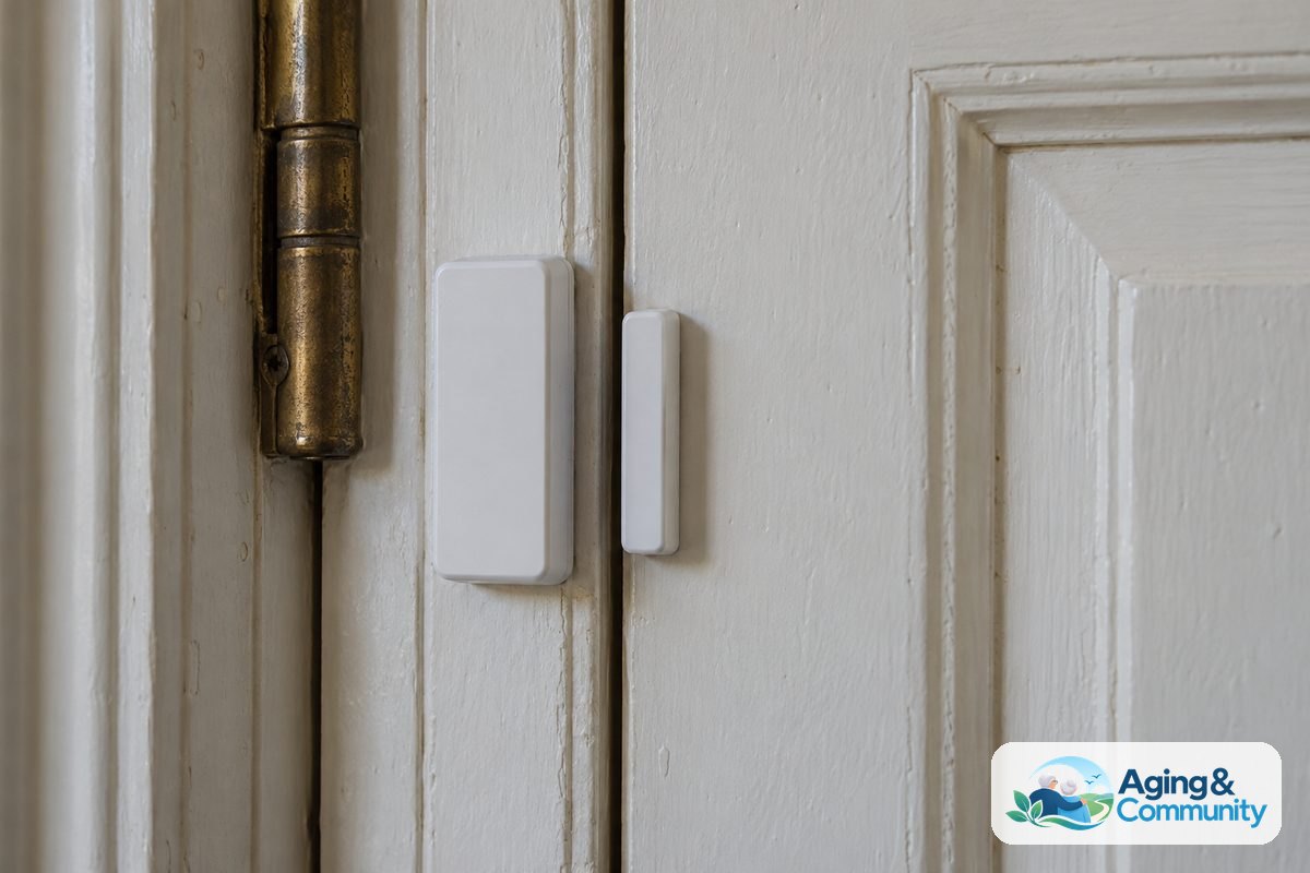 AI and Aging in Place: Practical Help at Home 4 A white two piece contact sensor is mounted across the edge of a closed entry door and its painted wooden frame.