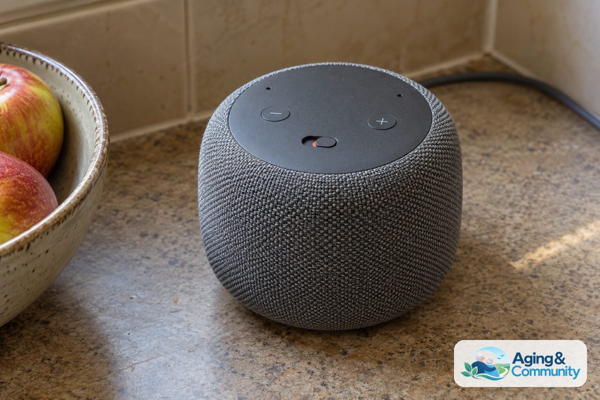 A fabric covered smart speaker with visible volume and microphone controls sits on a kitchen counter beside a fruit bowl.